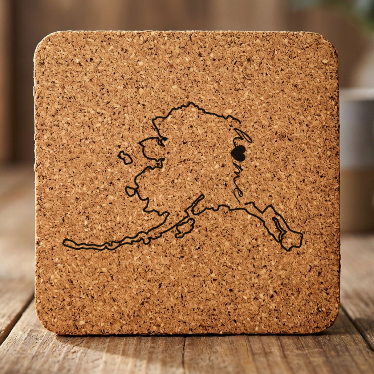 Alaska square cork coaster engraved with the state outline and home in script with a heart