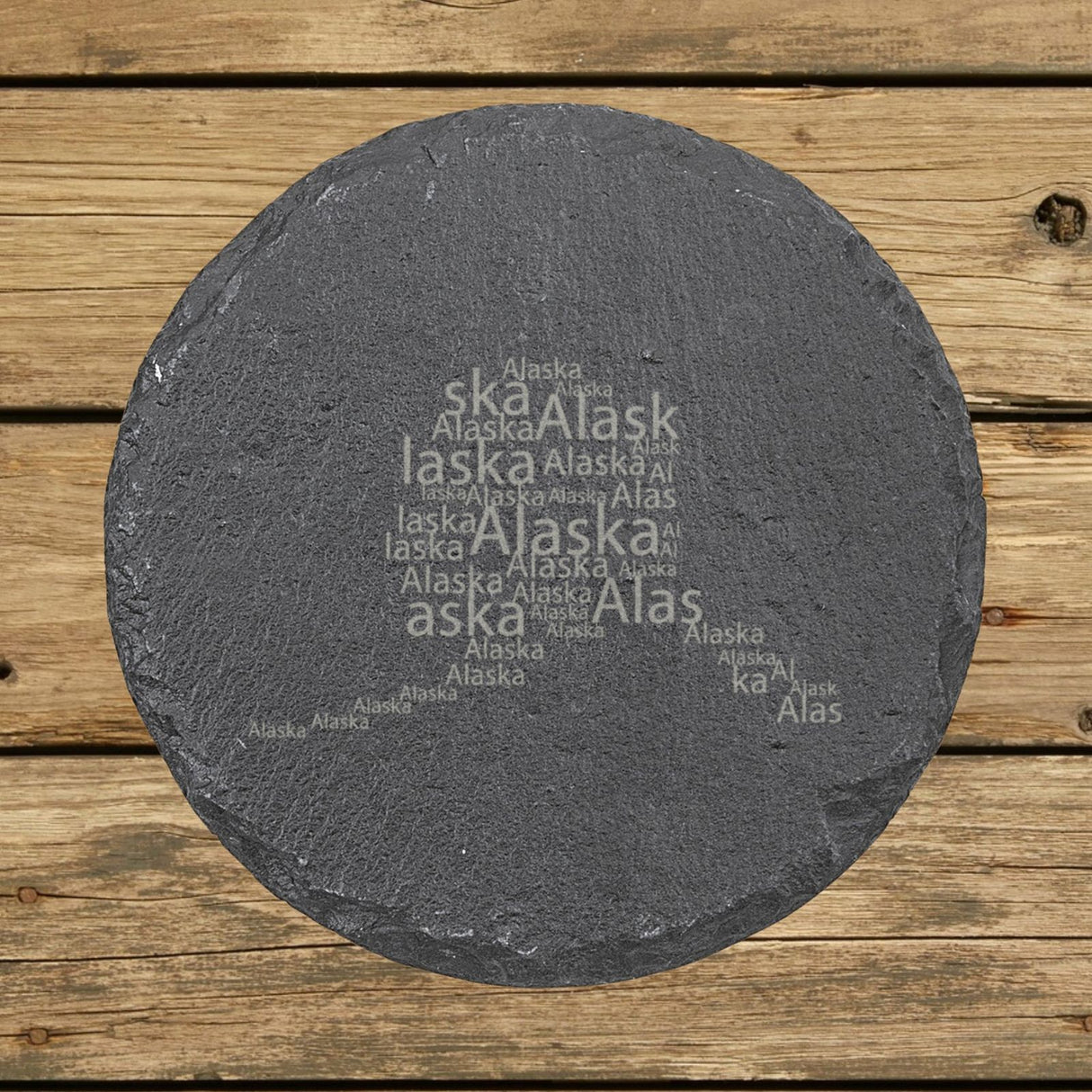 Alaska round slate coaster engraved with a word cloud of repeating Alaska text