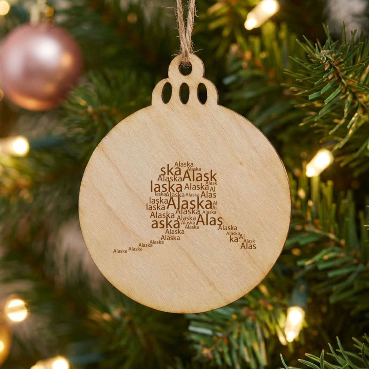 Alaska round wood Christmas ornament engraved with a word cloud of repeating Alaska text