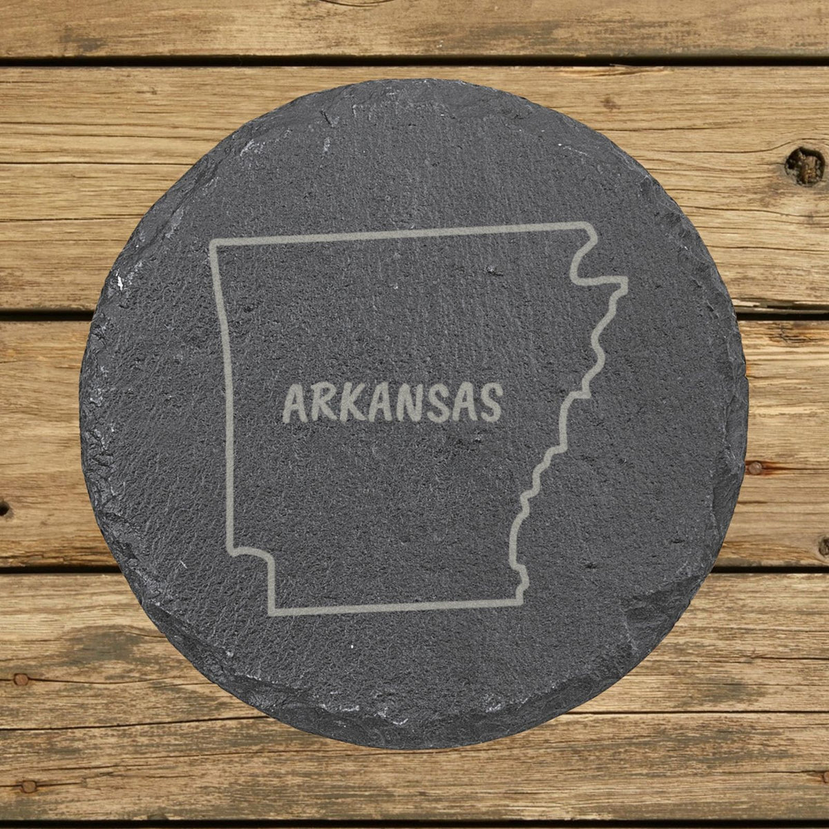 Arkansas round slate coaster engraved with the state outline and ARKANSAS in hand-drawn brush lettering