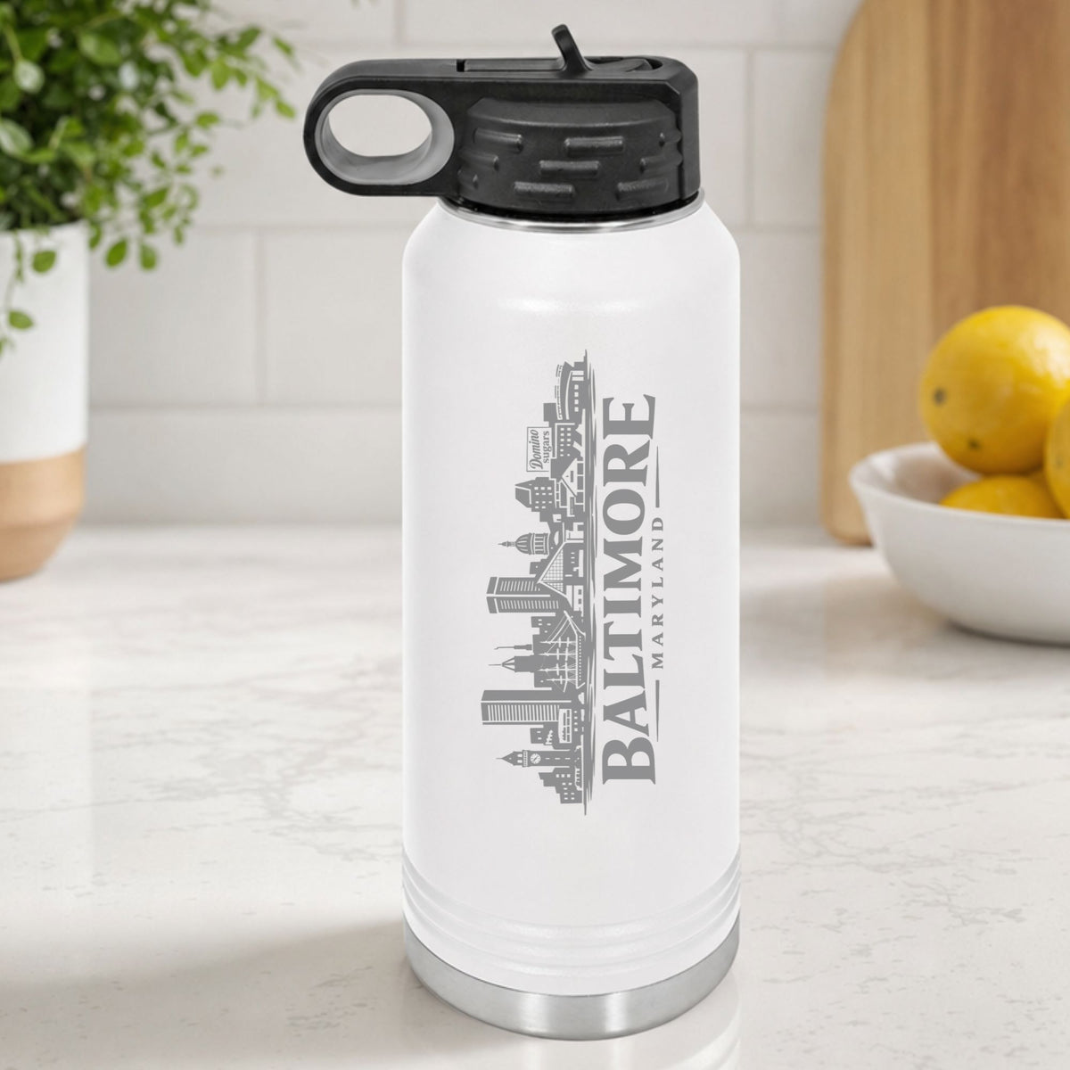 White 32 oz insulated water bottle laser engraved with the Baltimore, Maryland skyline running up the side, standing on a kitchen counter