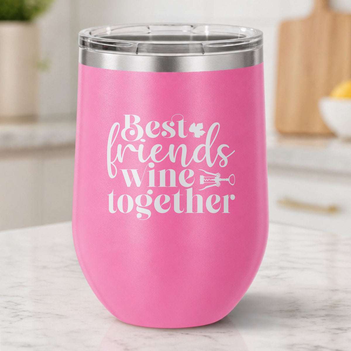 Pink 12 oz stemless wine tumbler laser engraved with "Best Friends Wine Together", on a kitchen counter