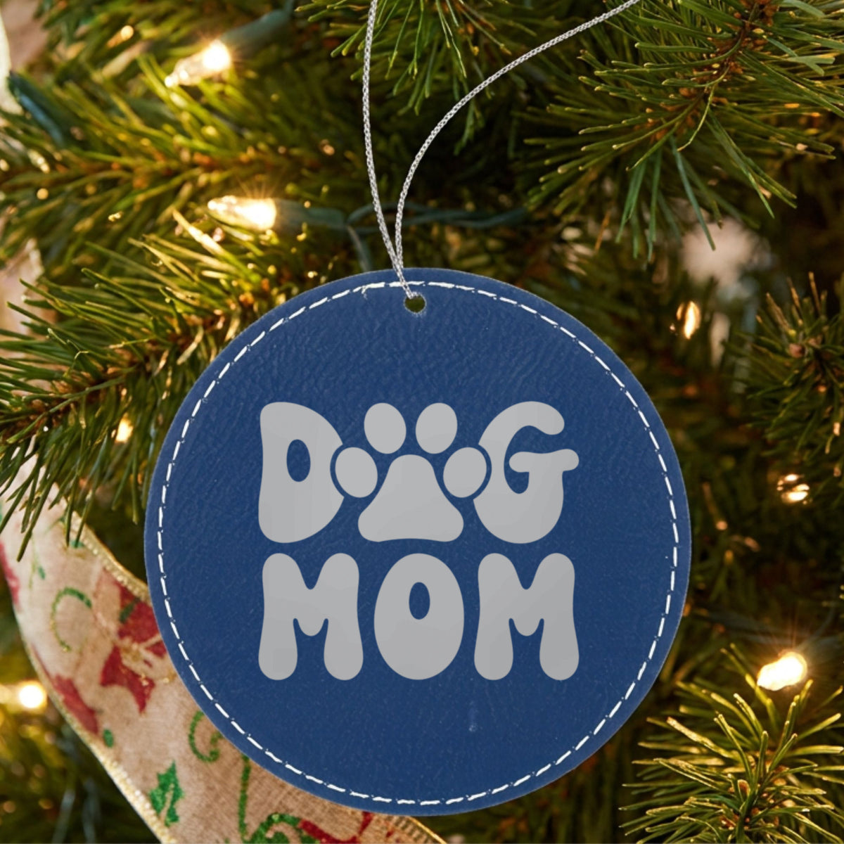 Blue leatherette Christmas ornament engraved with a retro bubble letter Dog Mom design with a paw print