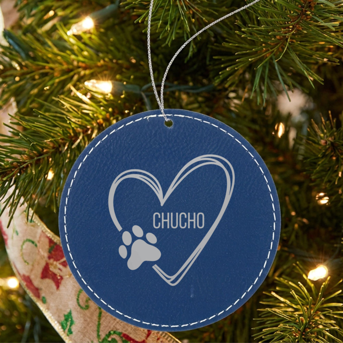 Blue leatherette Christmas ornament engraved with the heart and paw print design and a sample pet name