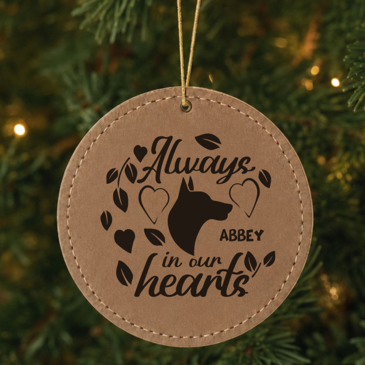 Brown leatherette Christmas ornament engraved with the Always in Our Hearts dog design and a sample pet name