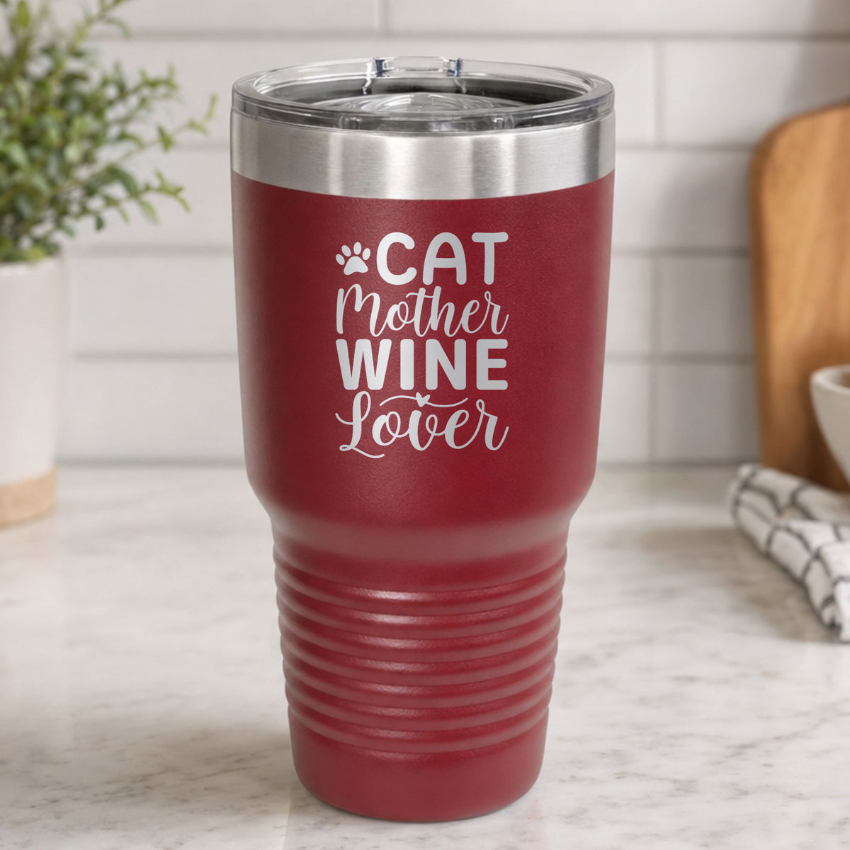 Maroon 30 oz tumbler laser engraved with "Cat Mother Wine Lover" and a paw print, on a kitchen counter