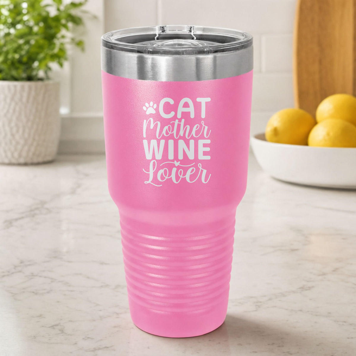 Pink 30 oz tumbler laser engraved with "Cat Mother Wine Lover" and a paw print, on a kitchen counter
