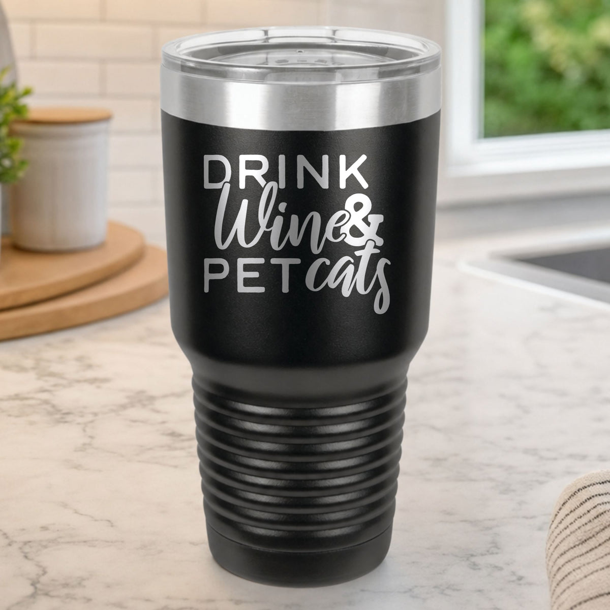 Black 30 oz tumbler laser engraved with "Drink Wine & Pet Cats", on a kitchen counter