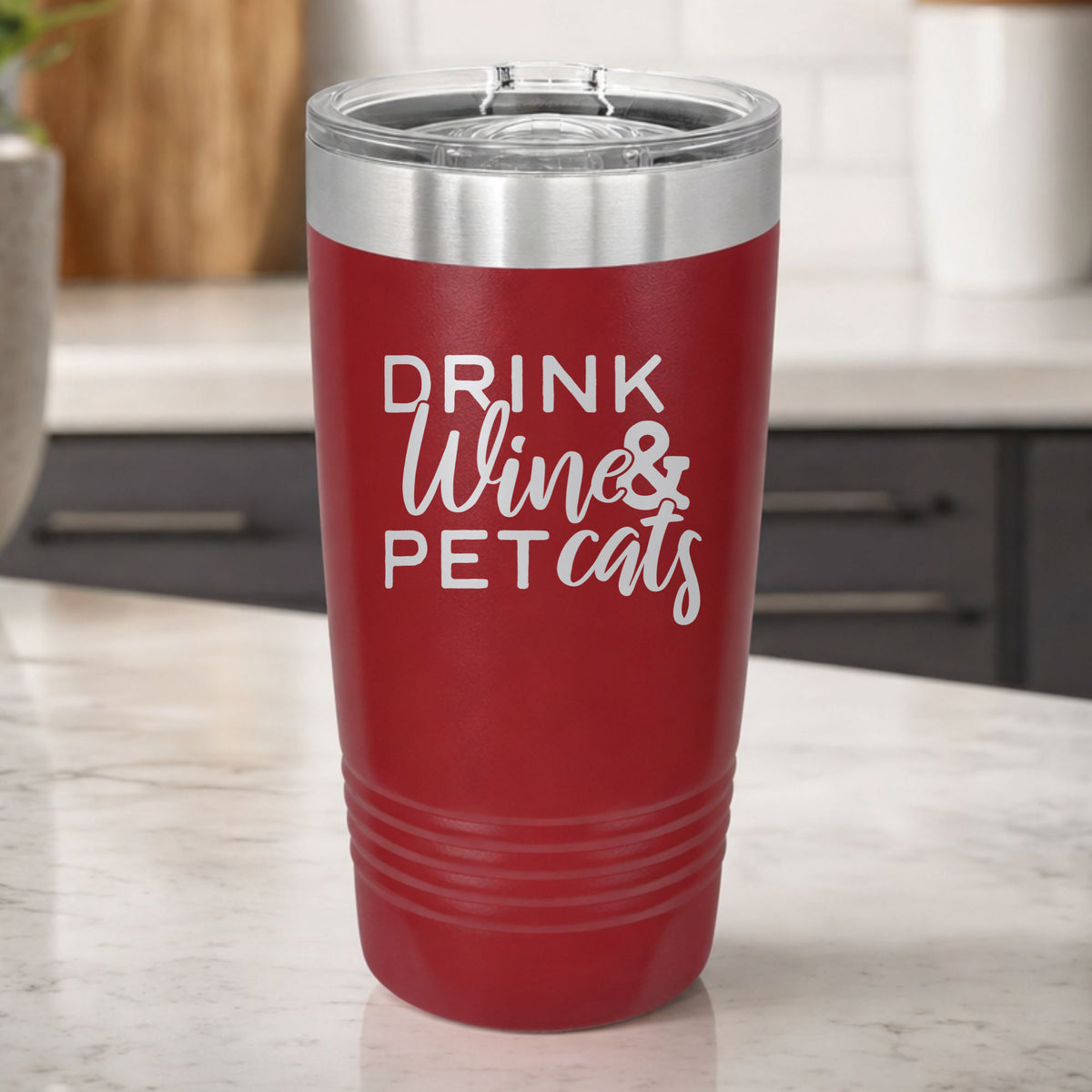 Maroon 20 oz tumbler laser engraved with "Drink Wine & Pet Cats", on a kitchen counter