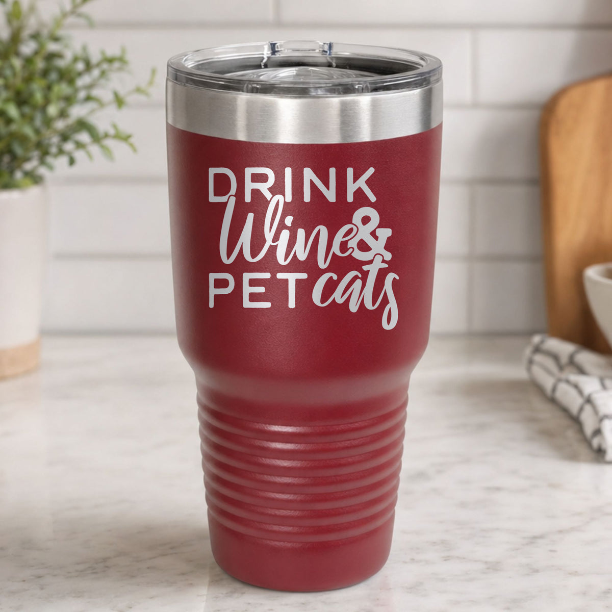 Maroon 30 oz tumbler laser engraved with "Drink Wine & Pet Cats", on a kitchen counter