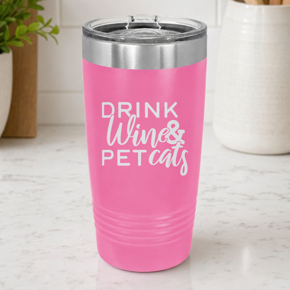 Pink 20 oz tumbler laser engraved with "Drink Wine & Pet Cats", on a kitchen counter