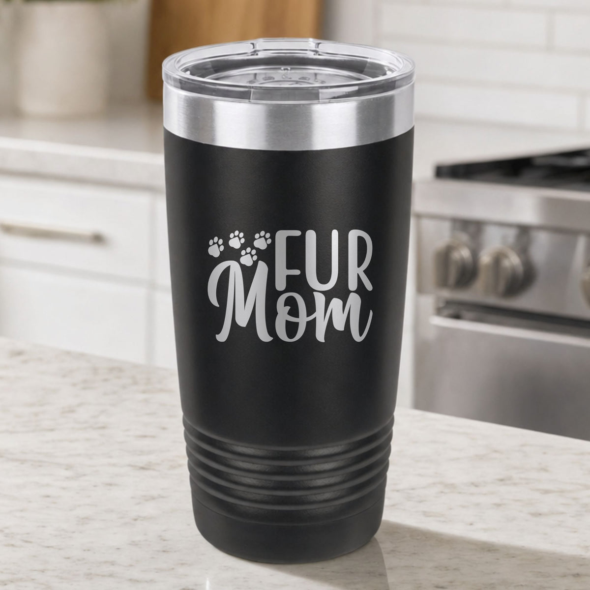 Black 20 oz tumbler laser engraved with "Fur Mom", plus paw prints, on a kitchen counter