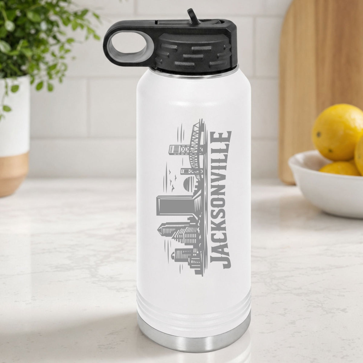 White 32 oz insulated water bottle laser engraved with the Jacksonville, Florida skyline running up the side, standing on a kitchen counter