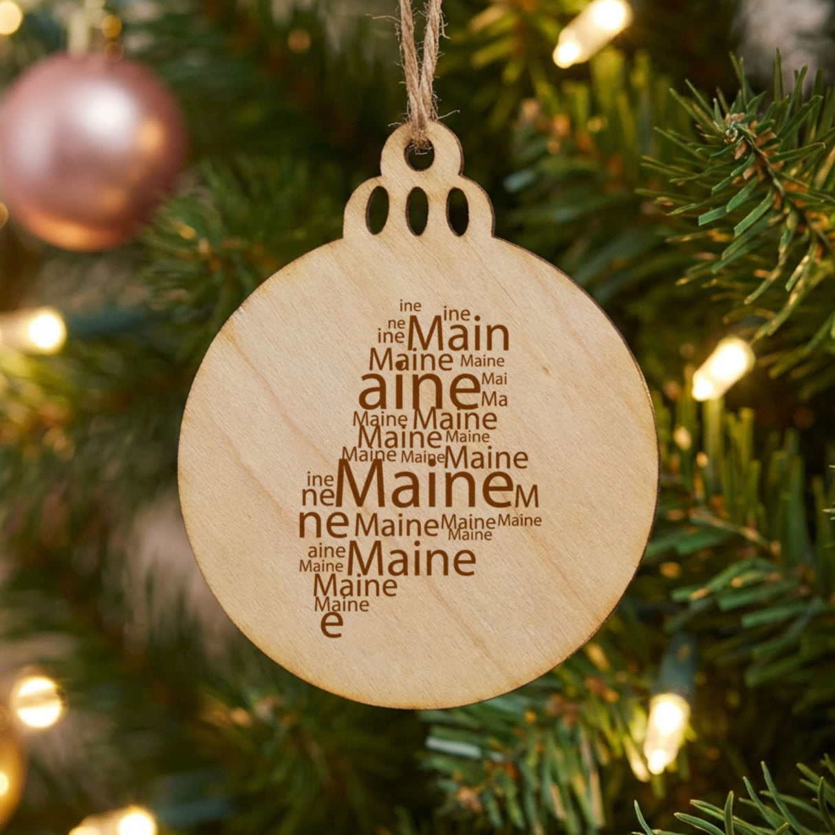 Maine round wood Christmas ornament engraved with a word cloud of repeating Maine text