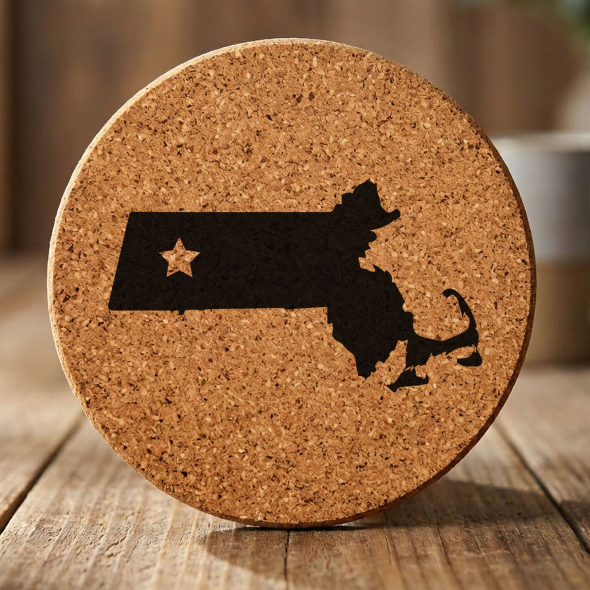 Massachusetts round cork coaster engraved with the state shape and a star