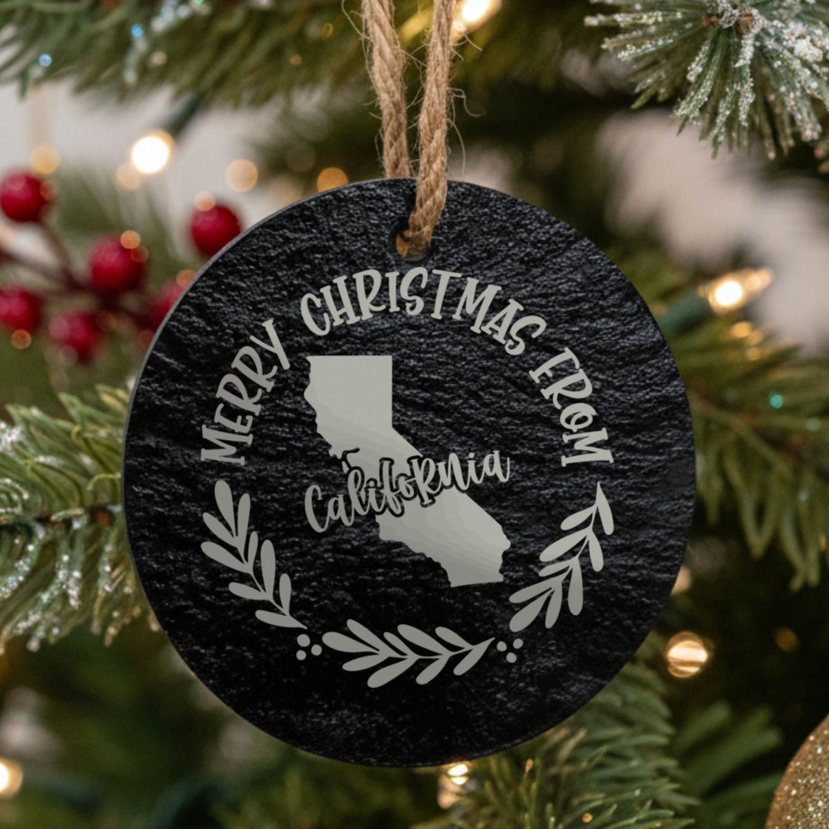 Round slate Christmas ornament engraved Merry Christmas From California, with the state shape in a laurel wreath