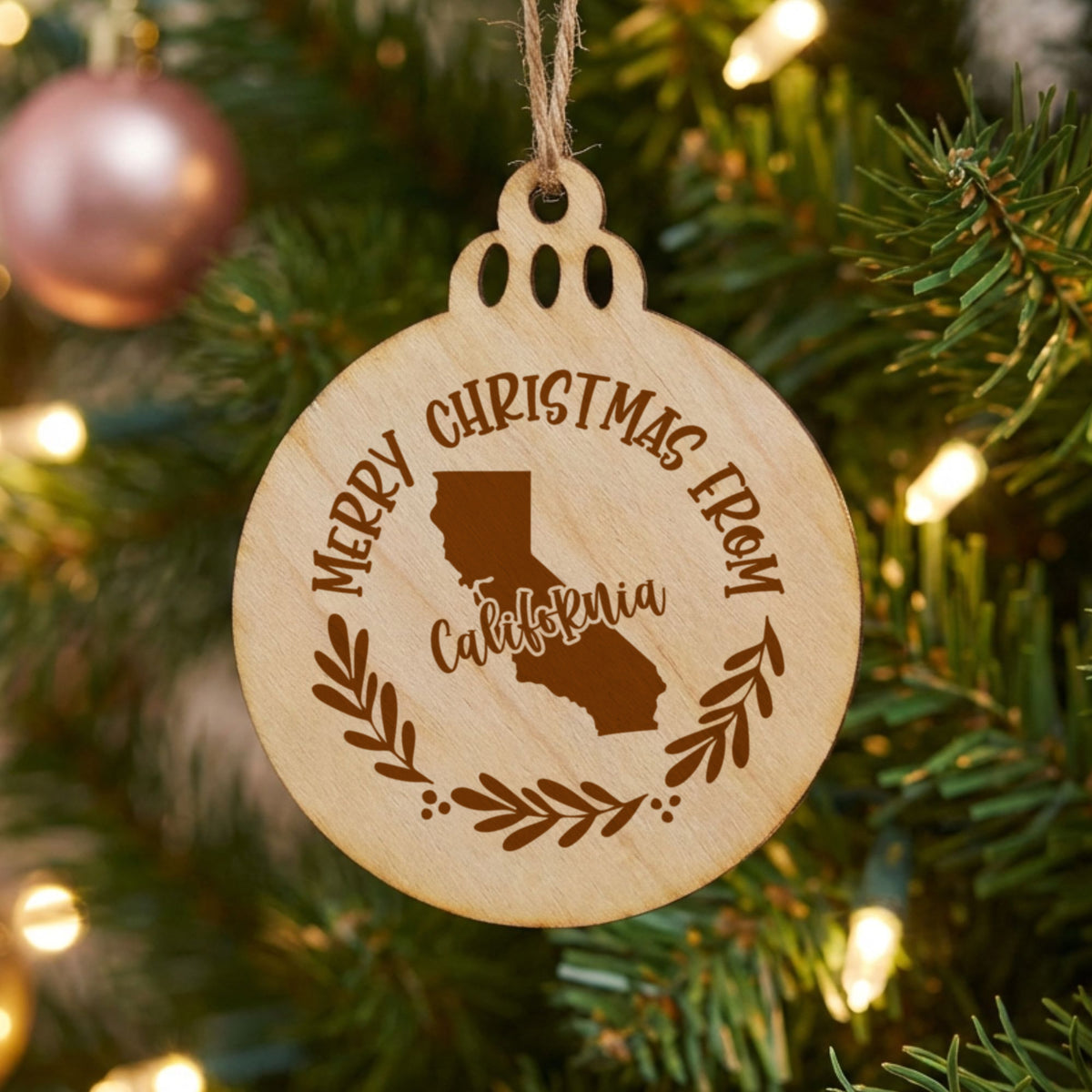 Round wood Christmas ornament engraved Merry Christmas From California, with the state shape in a laurel wreath