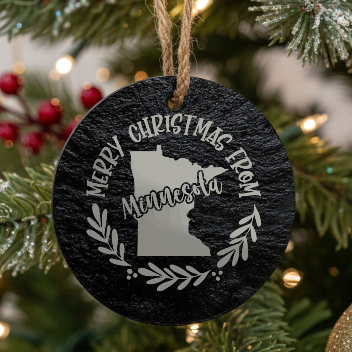 Round slate Christmas ornament engraved Merry Christmas From Minnesota, with the state shape in a laurel wreath