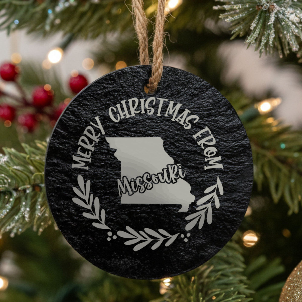 Round slate Christmas ornament engraved Merry Christmas From Missouri, with the state shape in a laurel wreath