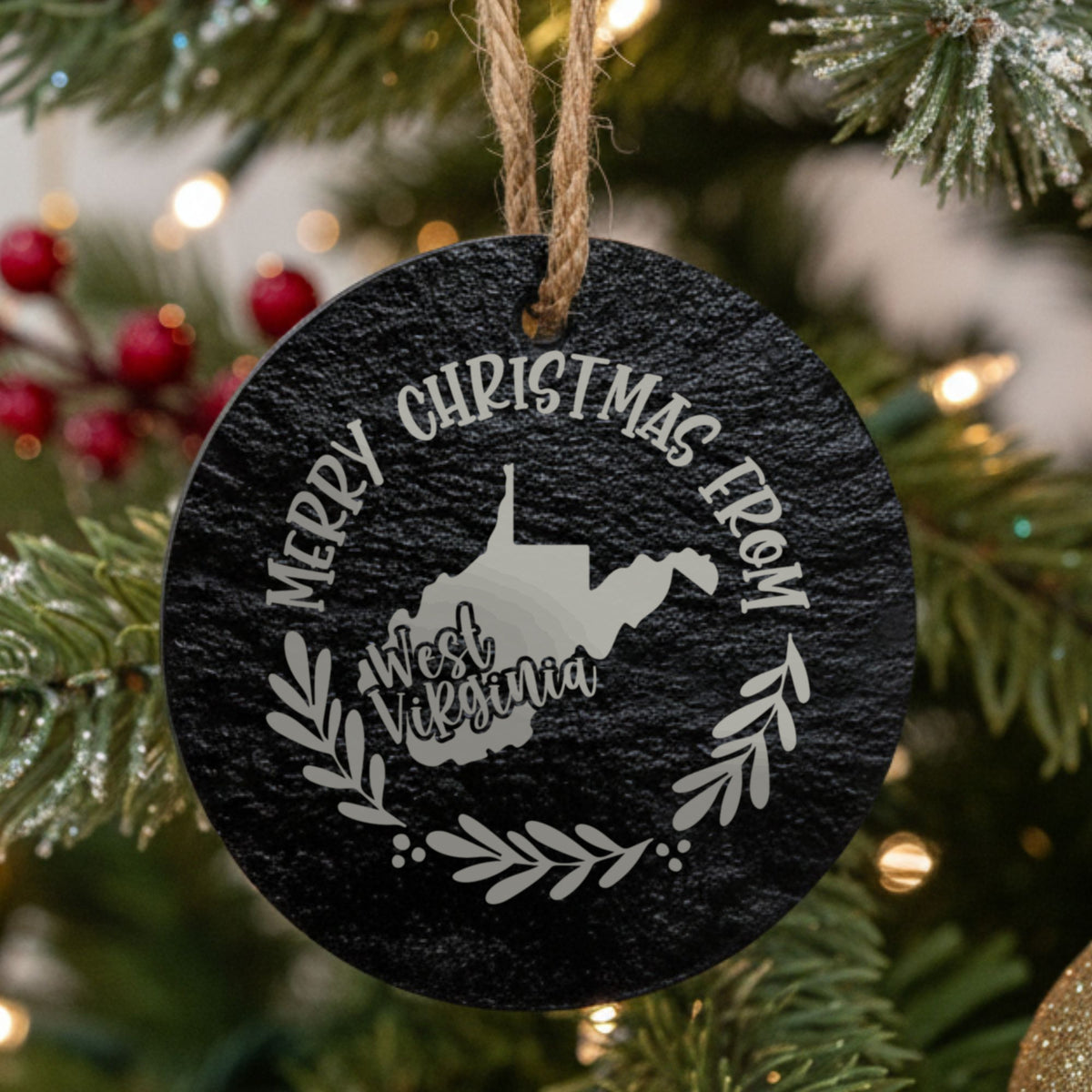 Round slate Christmas ornament engraved Merry Christmas From West Virginia, with the state shape in a laurel wreath