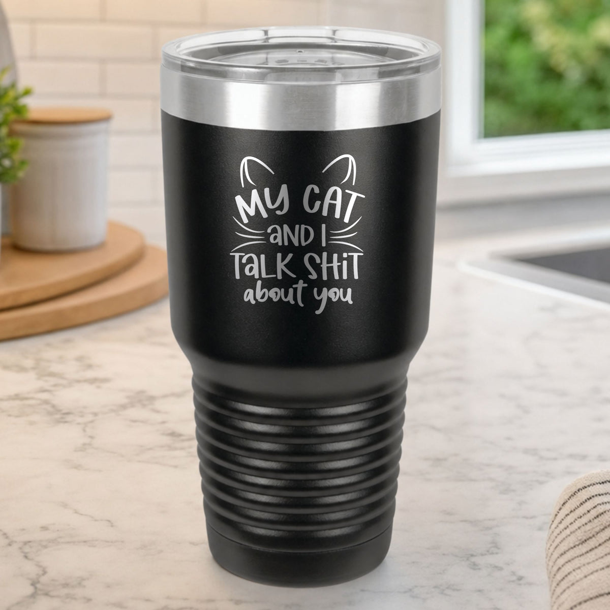 Black 30 oz tumbler laser engraved with "My Cat and I Talk Sh*t About You", plus cat ears and whiskers, on a kitchen counter