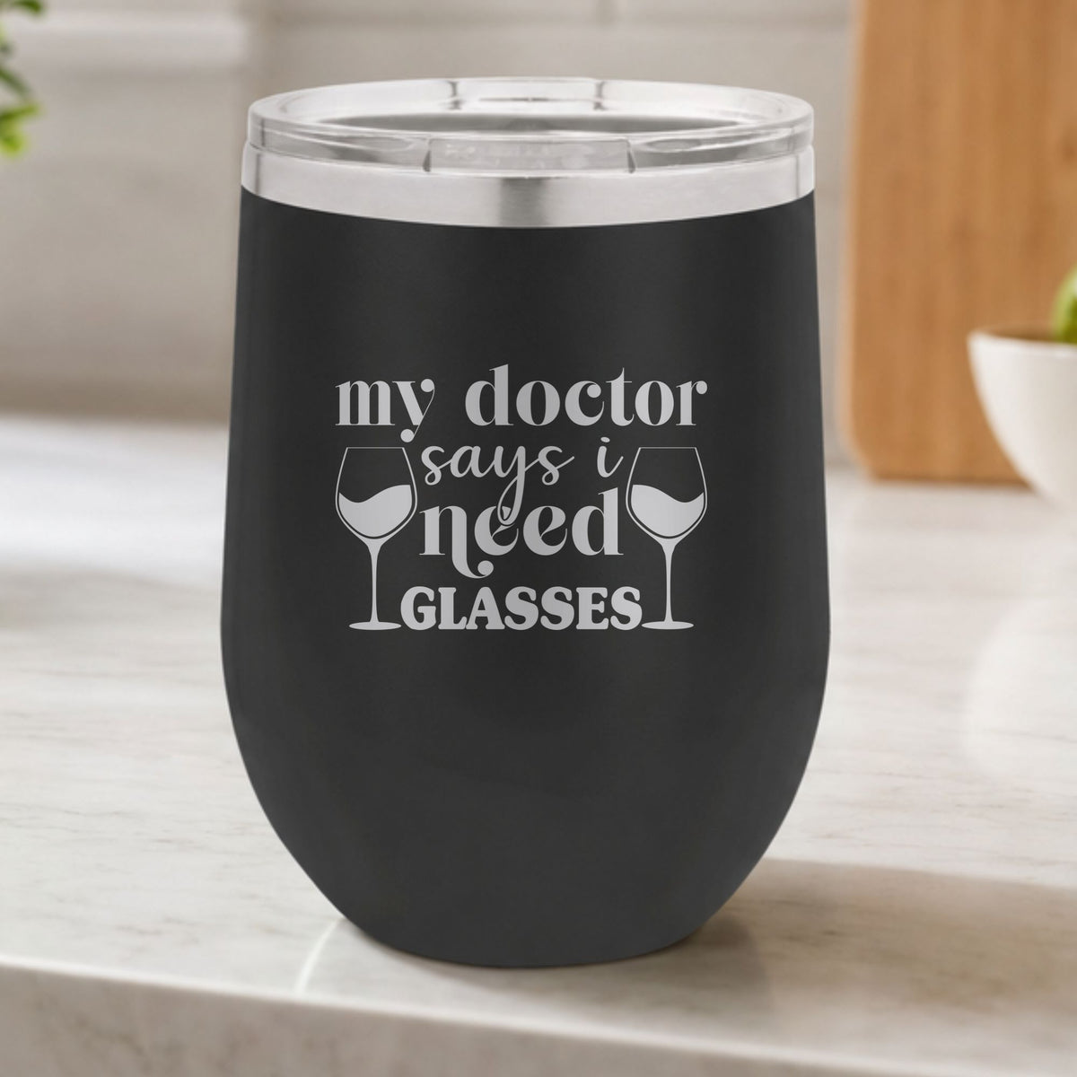 Black 12 oz stemless wine tumbler laser engraved with "My Doctor Says I Need Glasses", on a kitchen counter