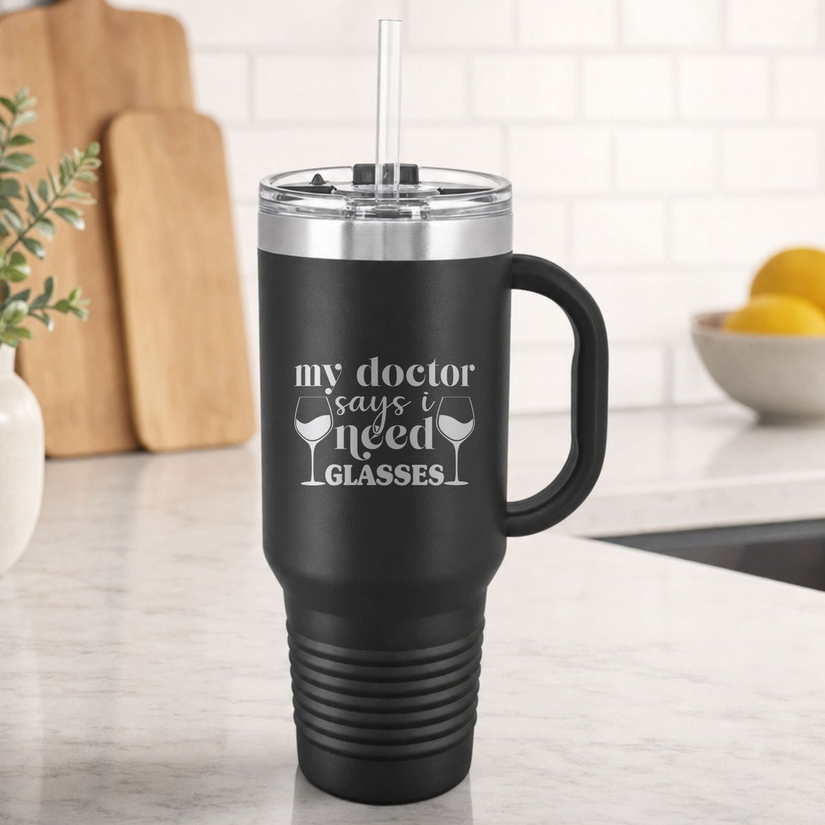 Black 40 oz tumbler with handle and straw laser engraved with "My Doctor Says I Need Glasses", on a kitchen counter