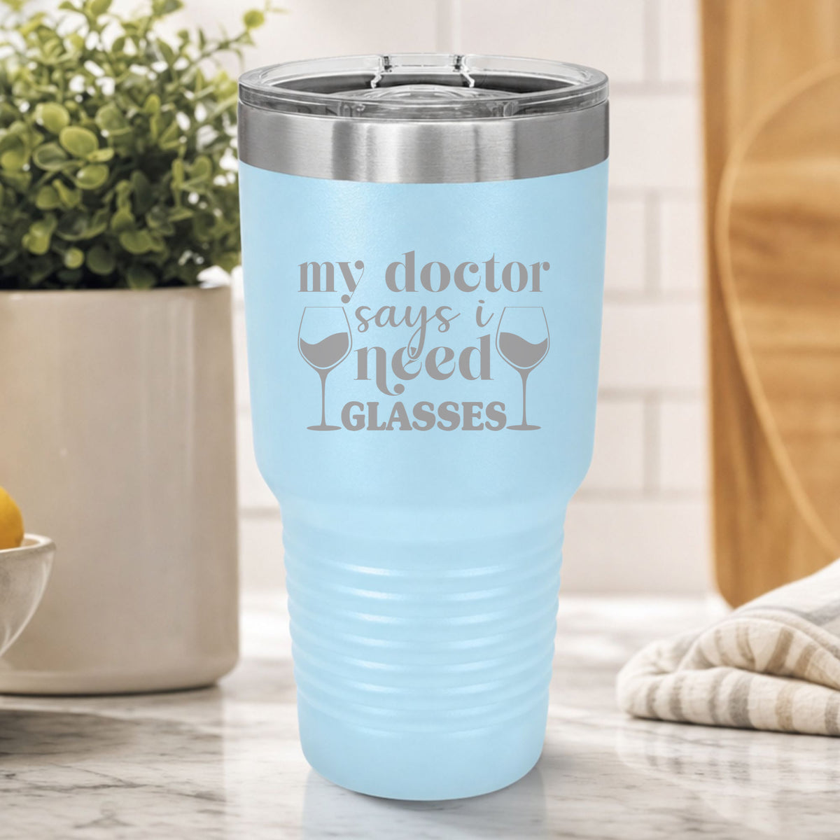 Light Blue 30 oz tumbler laser engraved with "My Doctor Says I Need Glasses", on a kitchen counter