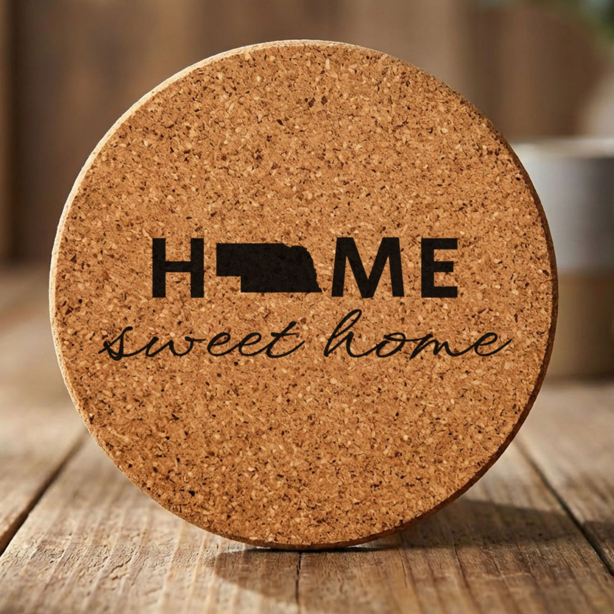 Nebraska round cork coaster engraved with HOME sweet home using the state shape as the letter O