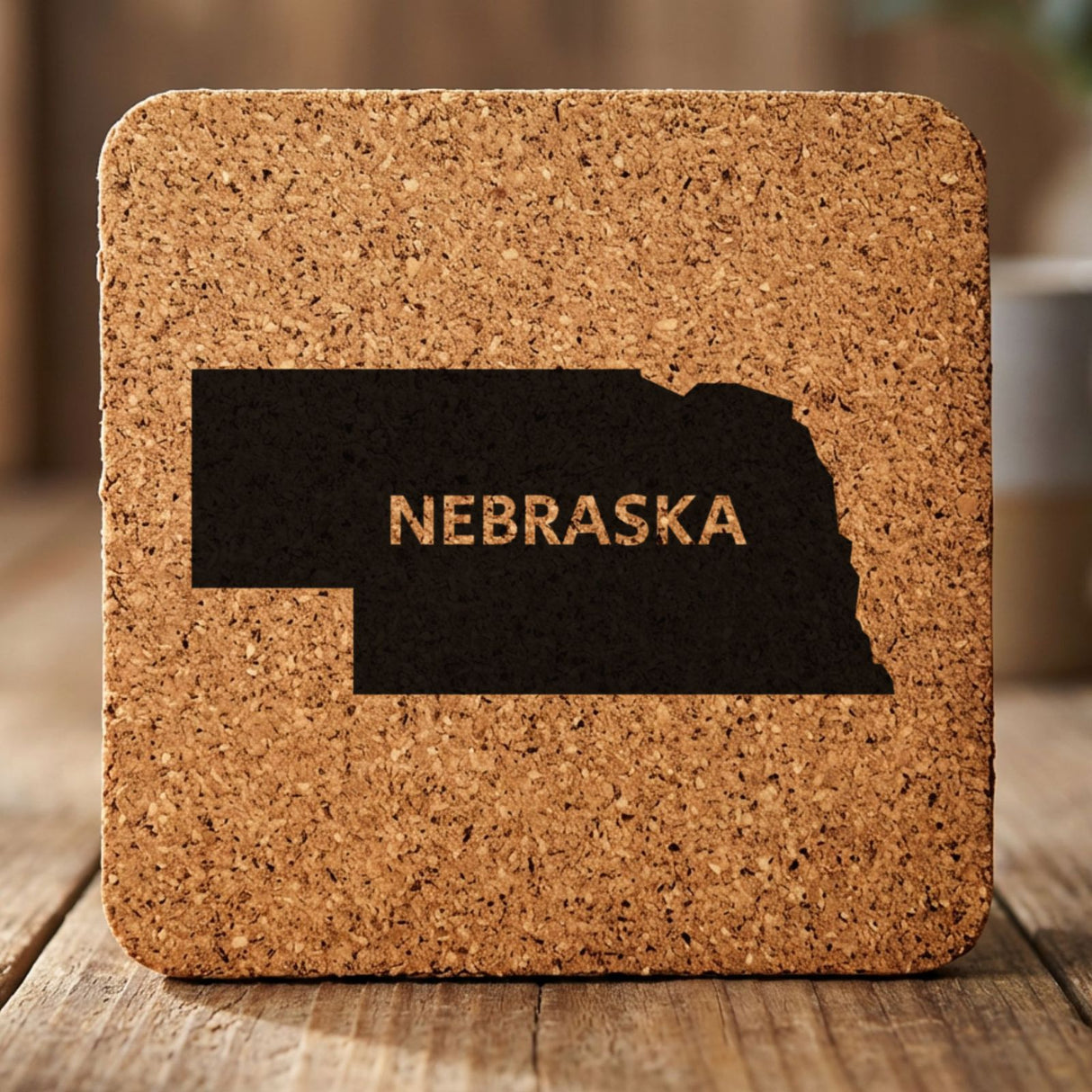 Nebraska square cork coaster engraved with the state shape and NEBRASKA in bold lettering
