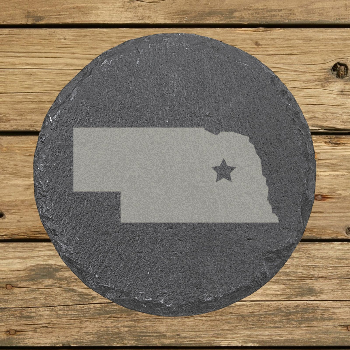 Nebraska round slate coaster engraved with the state shape and a star