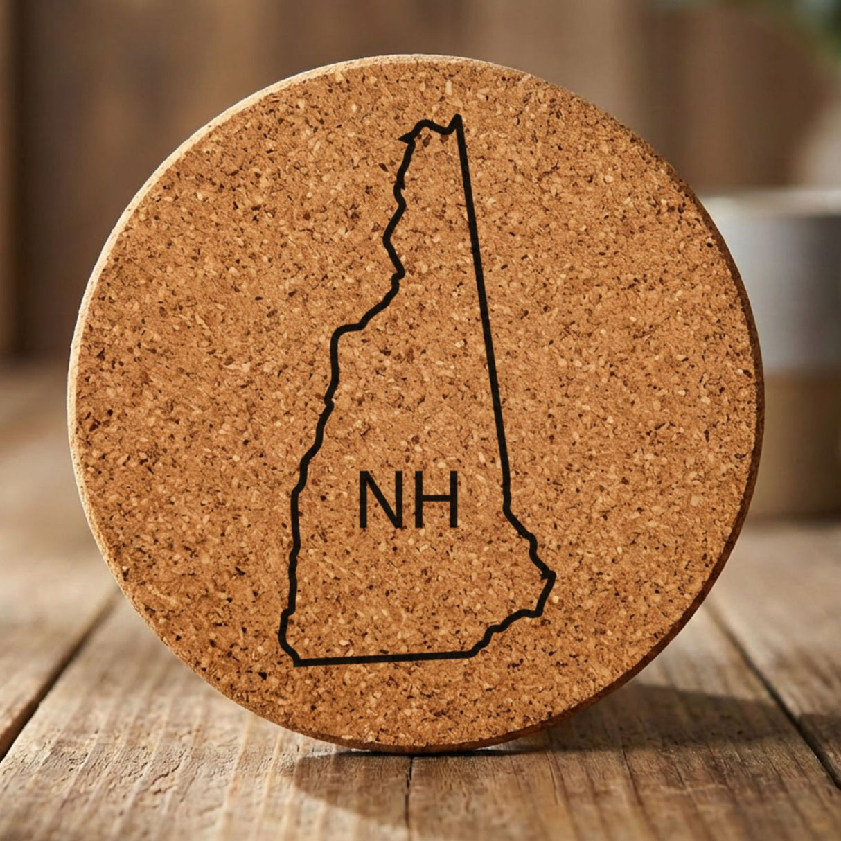 New Hampshire round cork coaster engraved with the state outline and NH initials