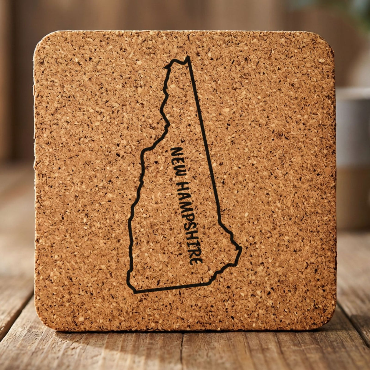 New Hampshire square cork coaster engraved with the state outline and NEW HAMPSHIRE running vertically