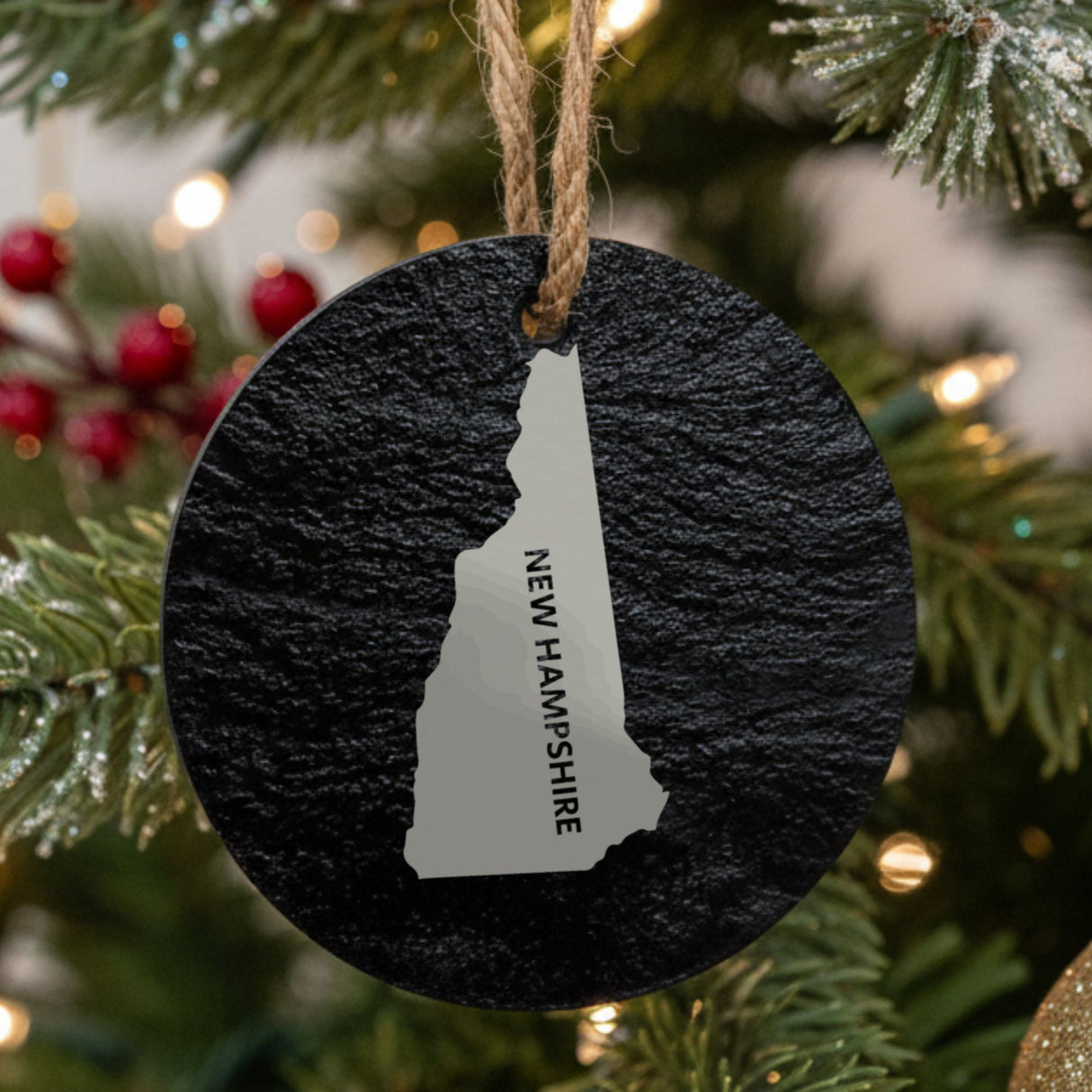 New Hampshire round slate Christmas ornament engraved with the state shape and NEW HAMPSHIRE in vertical lettering
