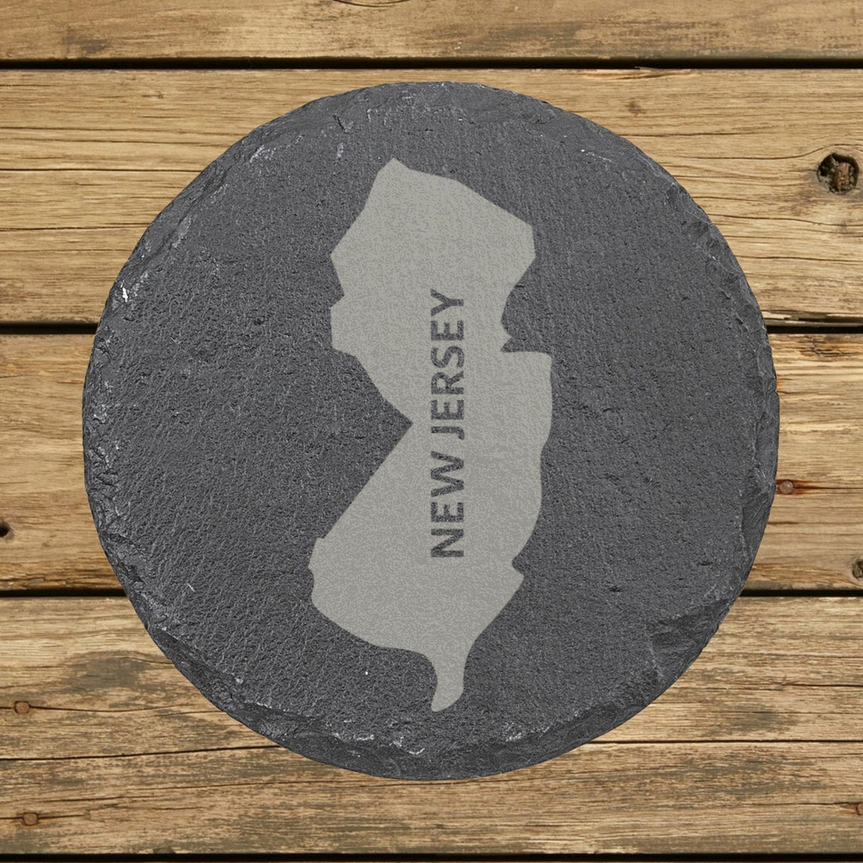 New Jersey round slate coaster with the engraved state shape and NEW JERSEY running vertically