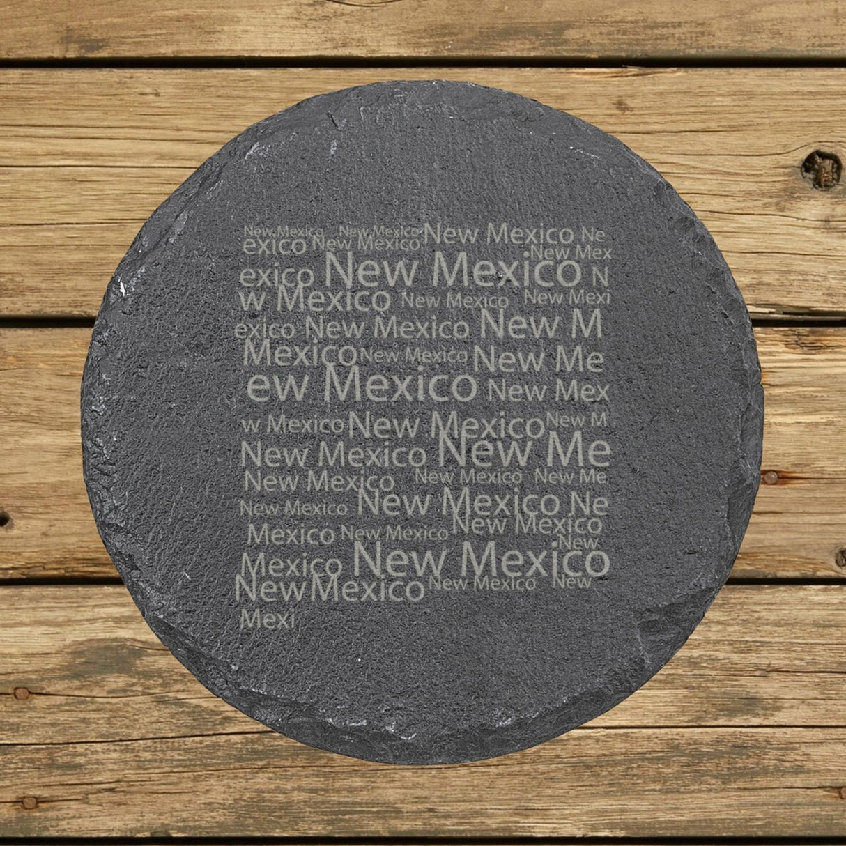 New Mexico round slate coaster engraved with a word cloud of repeating New Mexico text