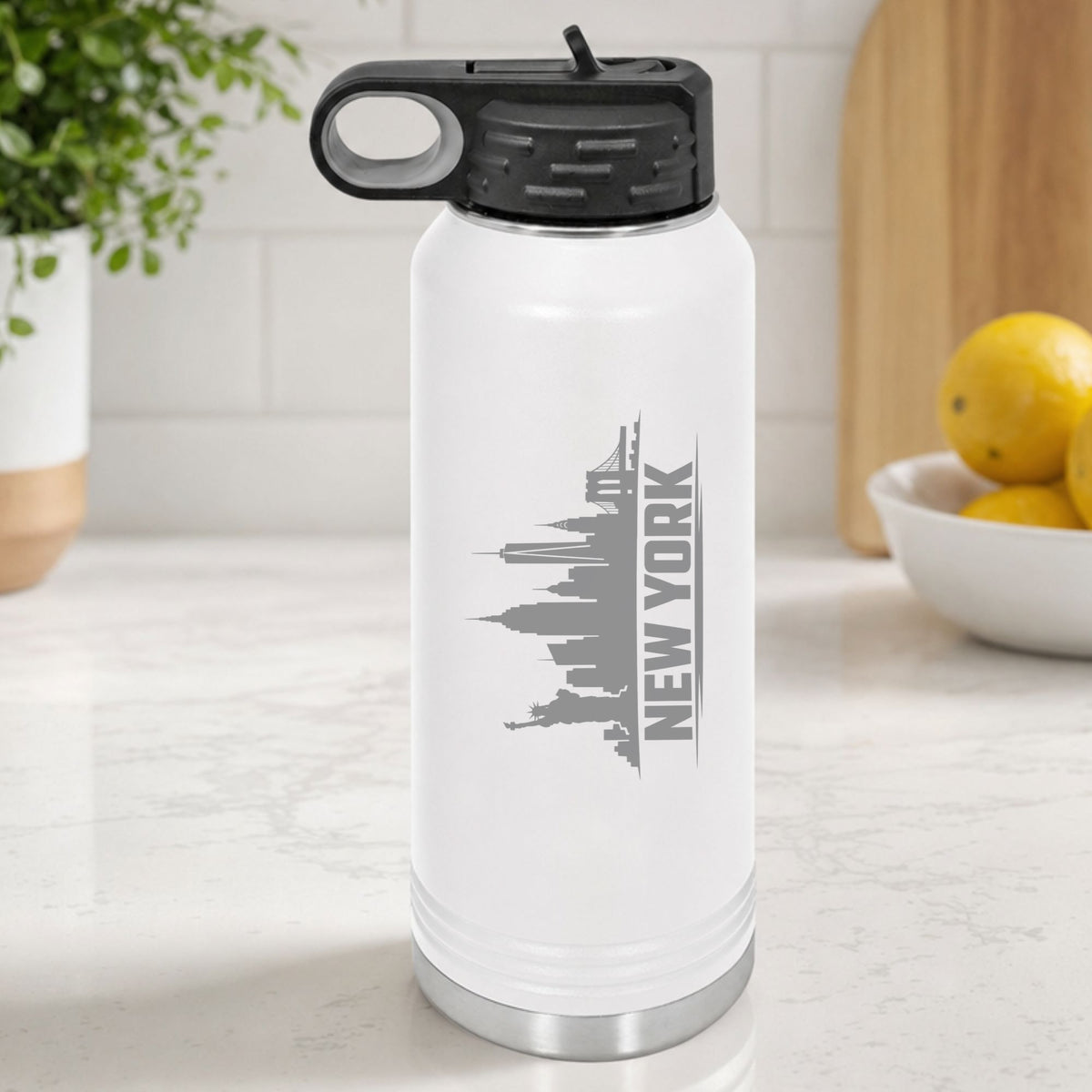 White 32 oz insulated water bottle laser engraved with the New York, New York skyline running up the side, standing on a kitchen counter