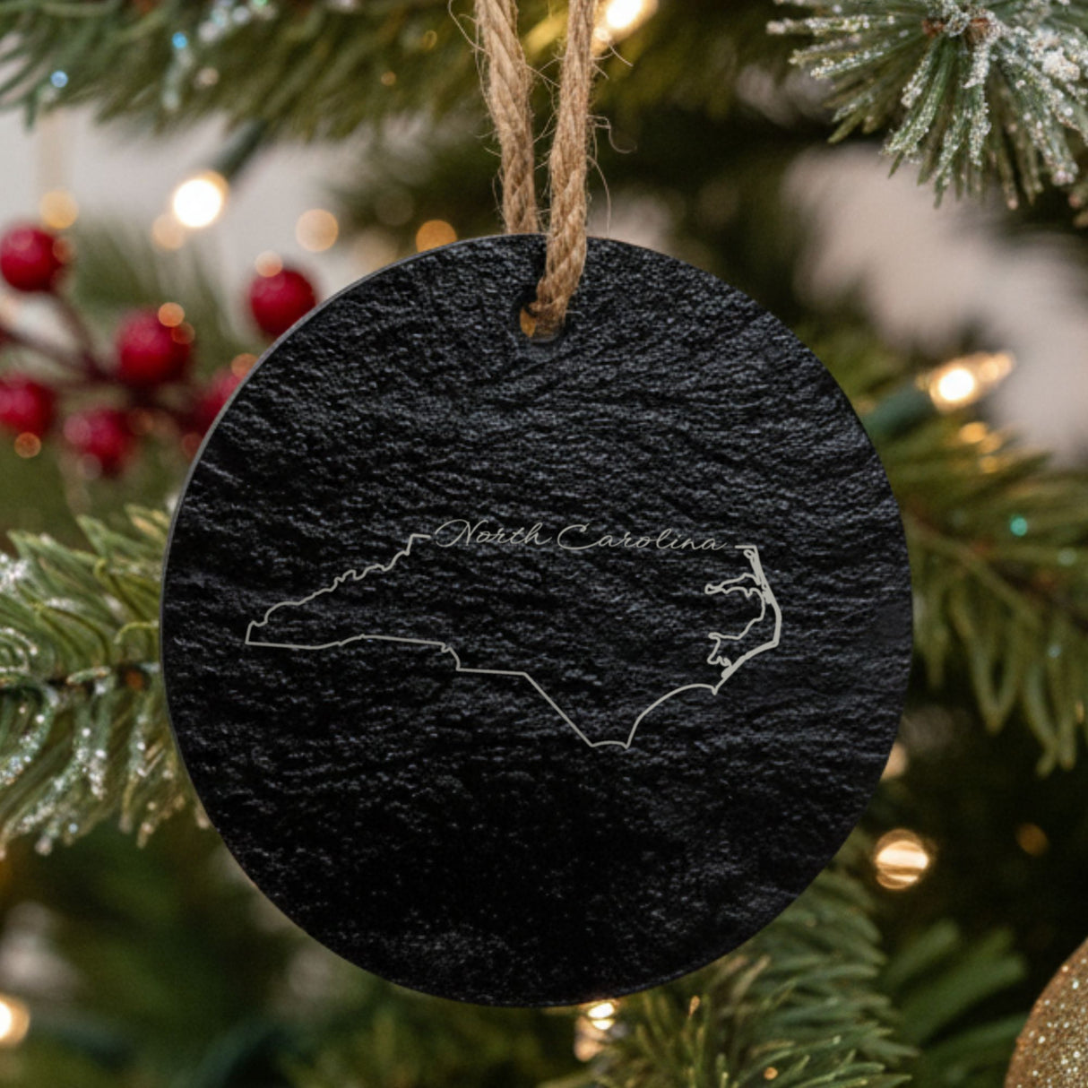 North Carolina round slate Christmas ornament engraved with the state outline and North Carolina in script lettering