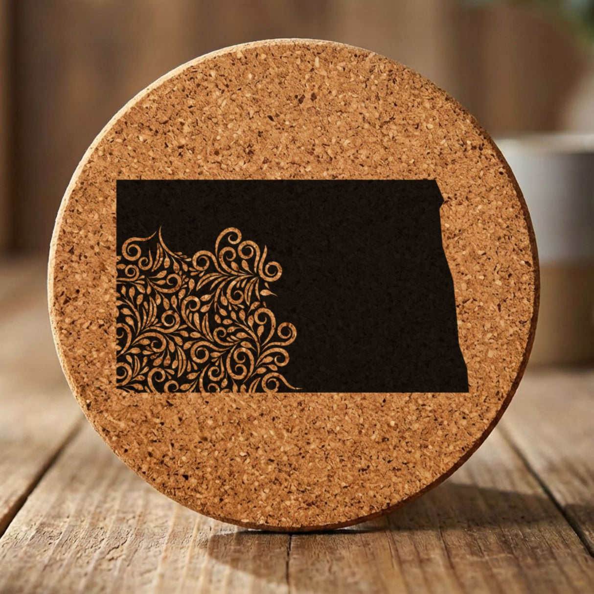 North Dakota round cork coaster engraved with the state shape in ornate floral scrollwork