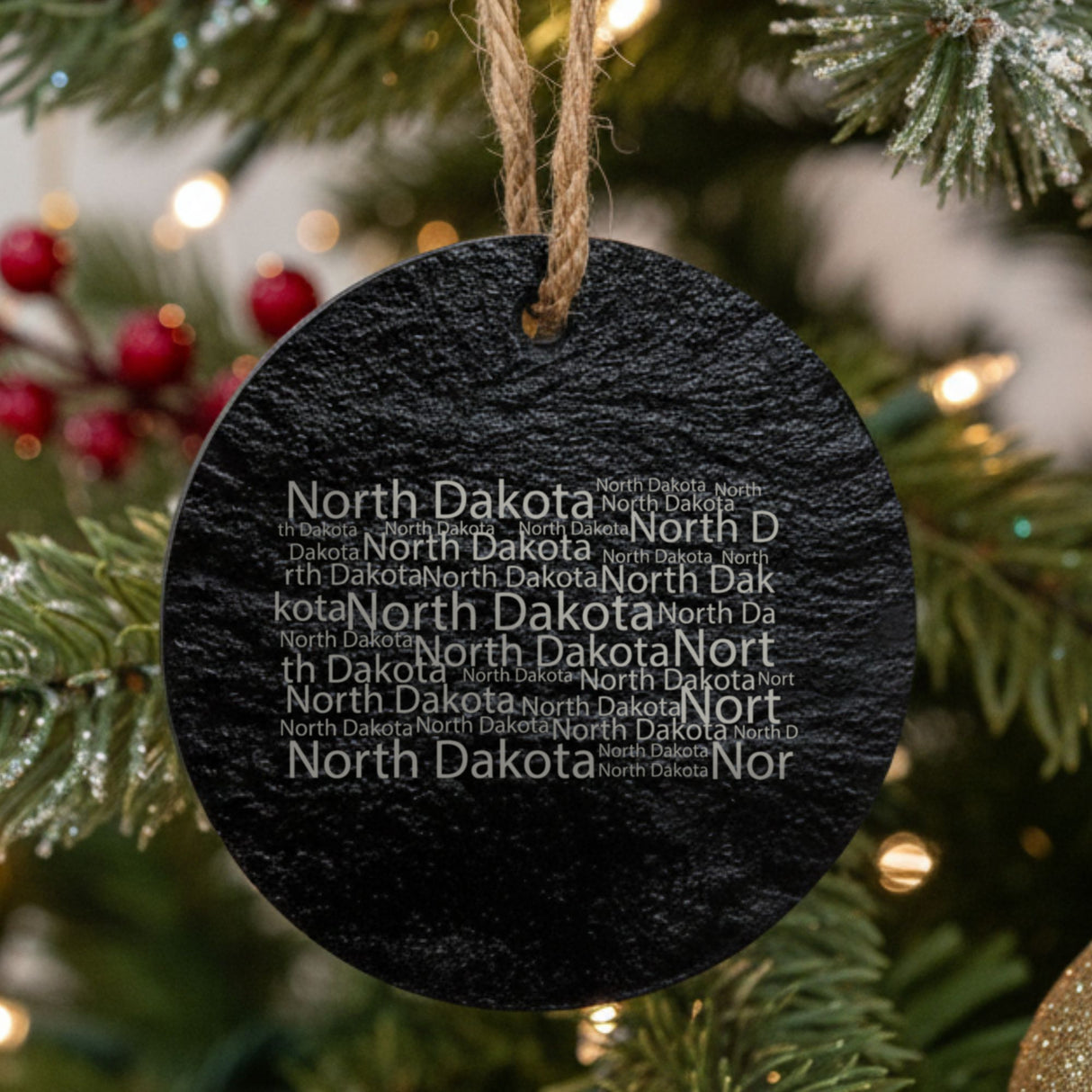 North Dakota round slate Christmas ornament engraved with a word cloud of repeating North Dakota text