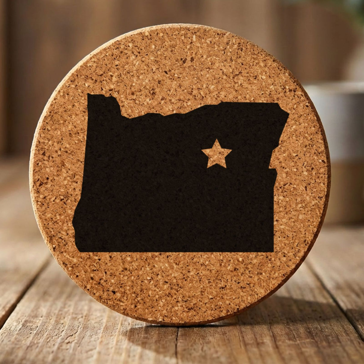 Oregon round cork coaster engraved with the state shape and a star