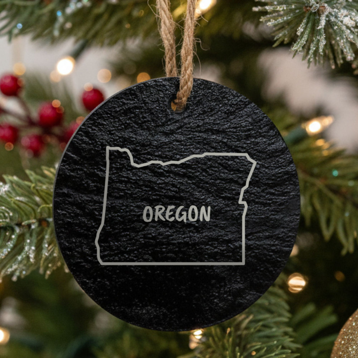 Oregon round slate Christmas ornament engraved with the state outline and OREGON in hand-drawn brush lettering