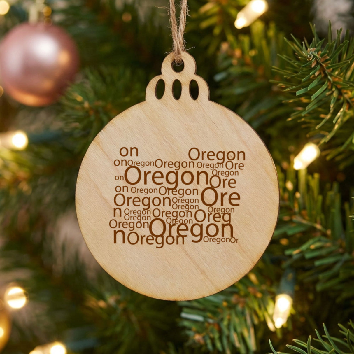 Oregon round wood Christmas ornament engraved with a word cloud of repeating Oregon text