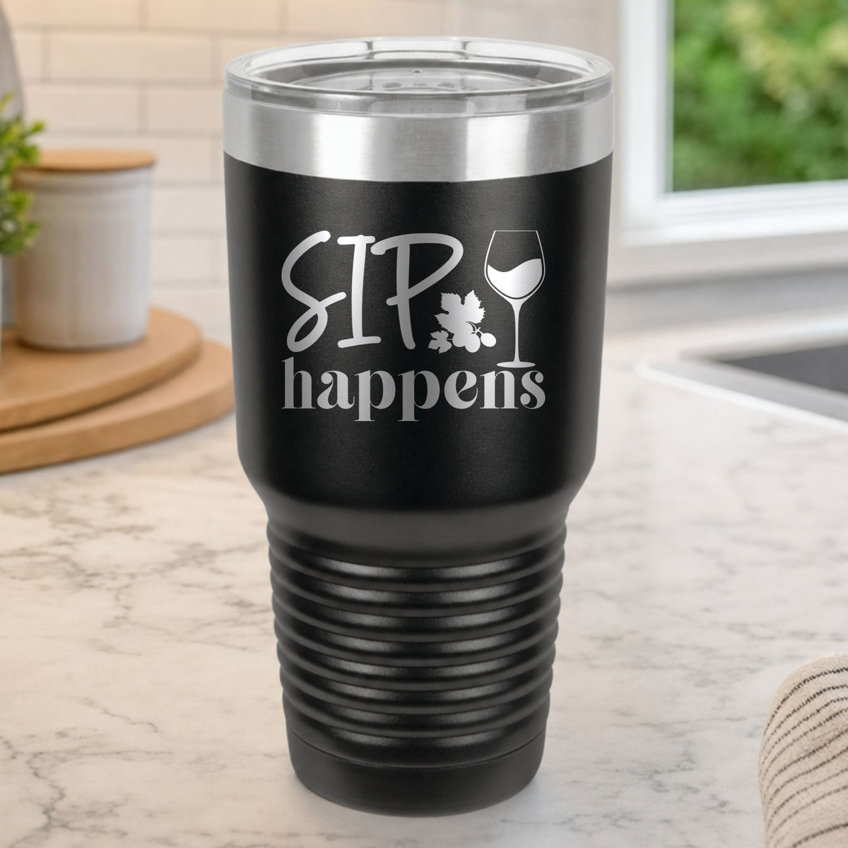 Black 30 oz tumbler laser engraved with "Sip Happens", on a kitchen counter
