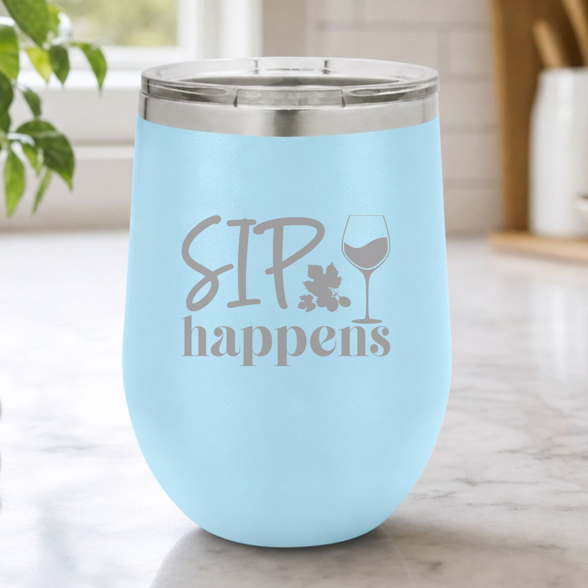 Light Blue 12 oz stemless wine tumbler laser engraved with "Sip Happens", on a kitchen counter