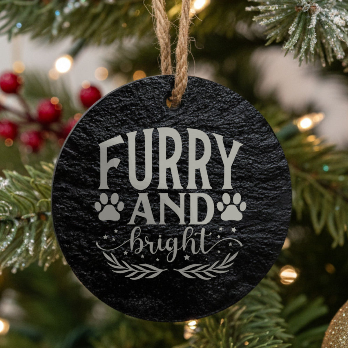 Round black slate Christmas ornament, laser engraved in white with Furry and Bright with paw prints, stars and a sprig