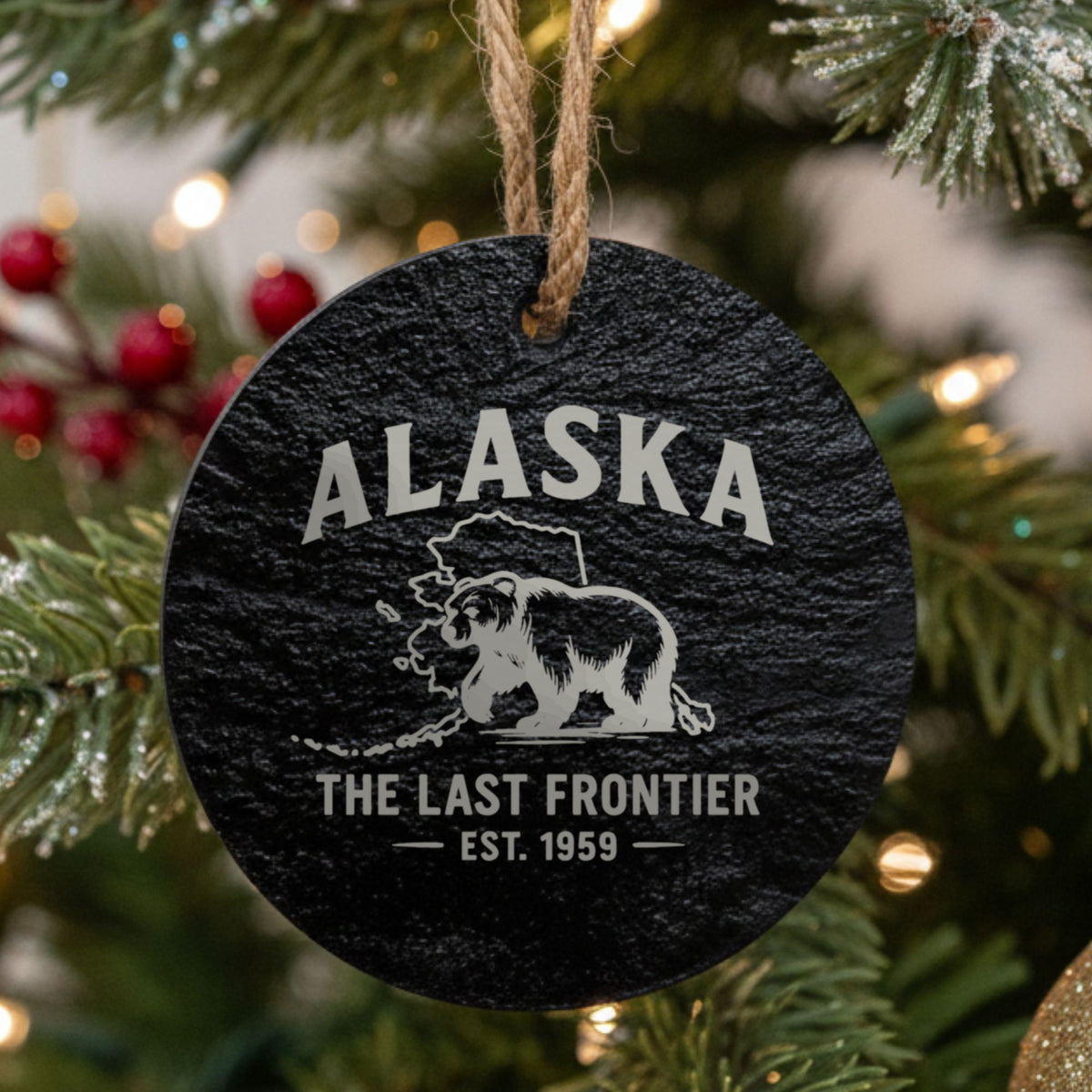 Round slate Christmas ornament laser engraved with an Alaska design of a grizzly bear crossing the state map