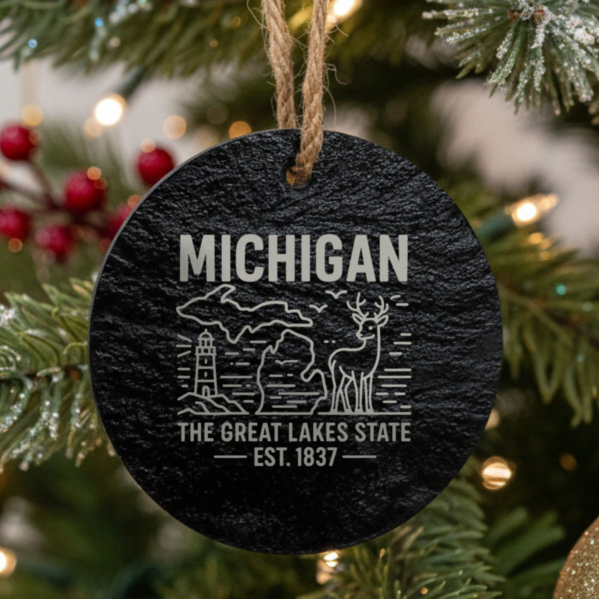 Round slate Christmas ornament laser engraved with a Michigan design of a lighthouse, a whitetail buck and both peninsulas