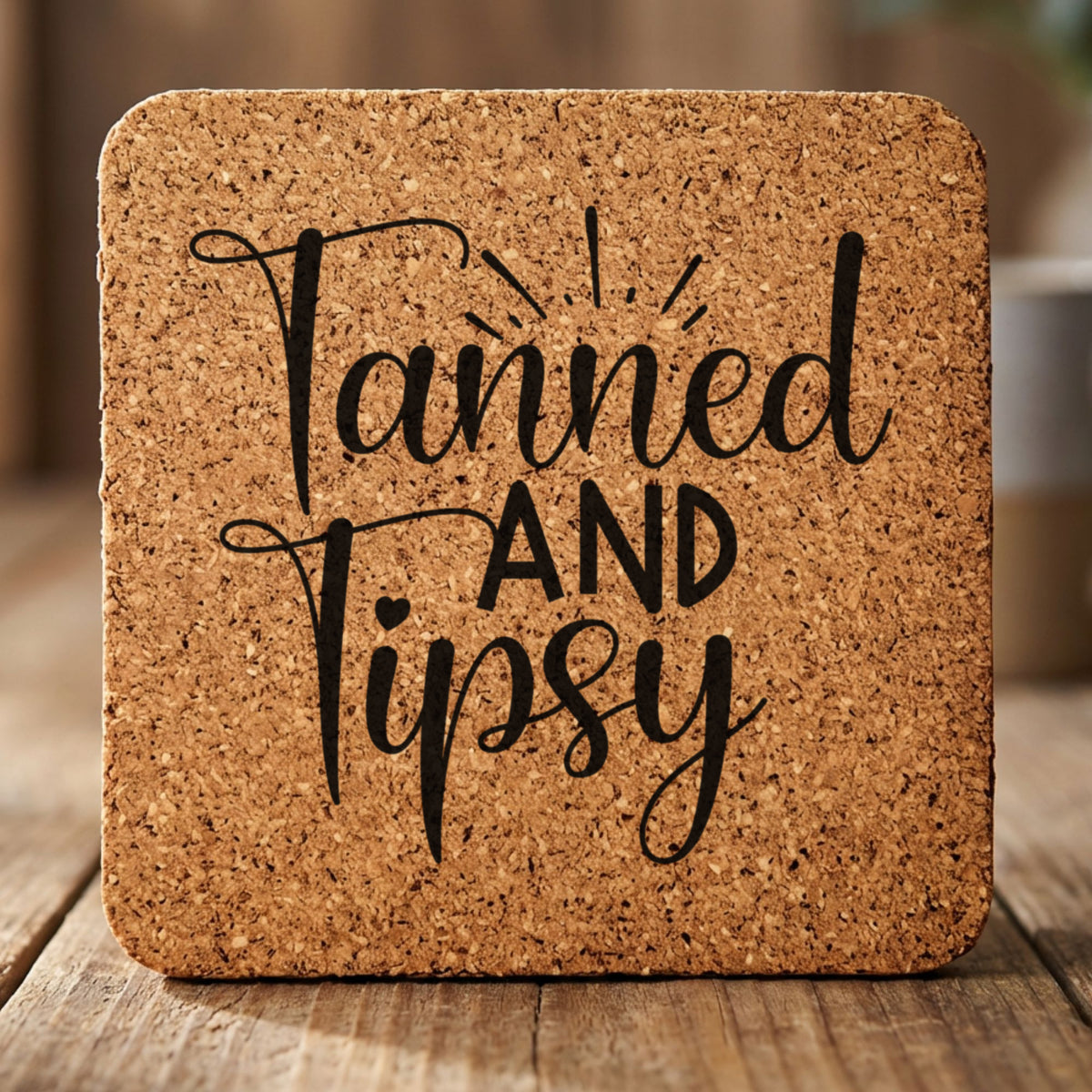 Square cork coaster laser engraved with "Tanned and Tipsy"