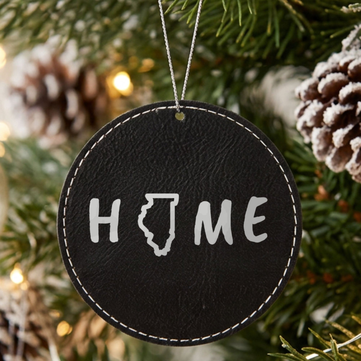 Black leatherette round Christmas ornament laser engraved with the Illinois HOME Outline design, hanging on a tree